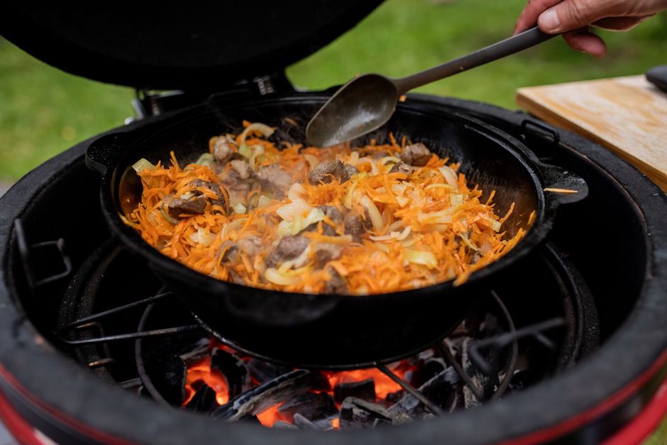куски зайца томятся с овощами в тяжёлой кастрюле