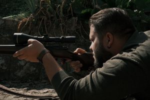 Охотник наблюдает опушку через дневной прицел
