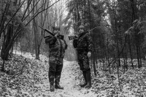 Охотник регулирует верхний слой одежды на лесной тропе