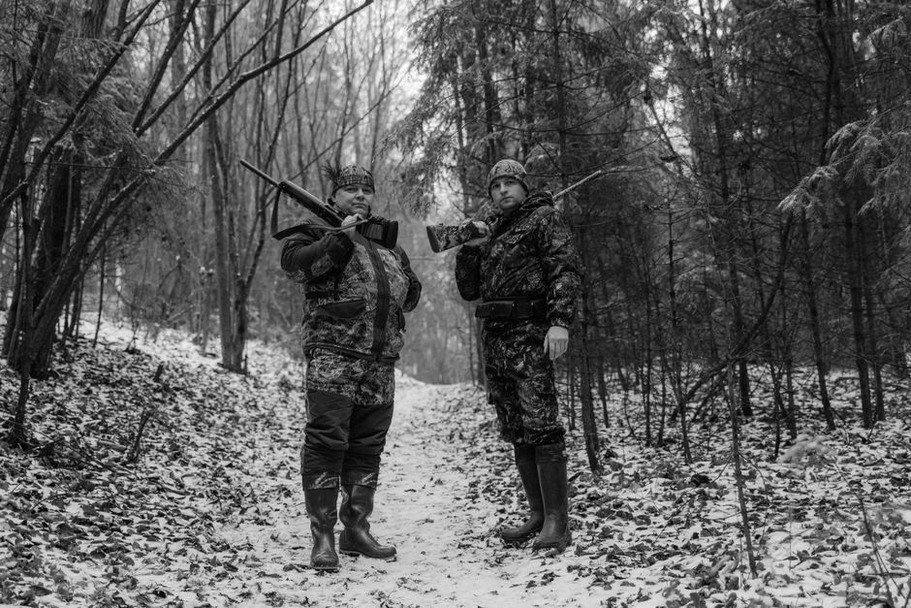 Охотник регулирует верхний слой одежды на лесной тропе